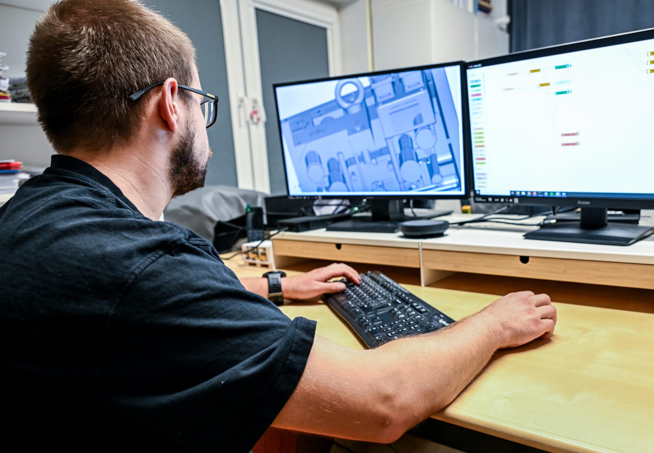 Mężczyzna pracujący przy biurku z dwoma monitorami